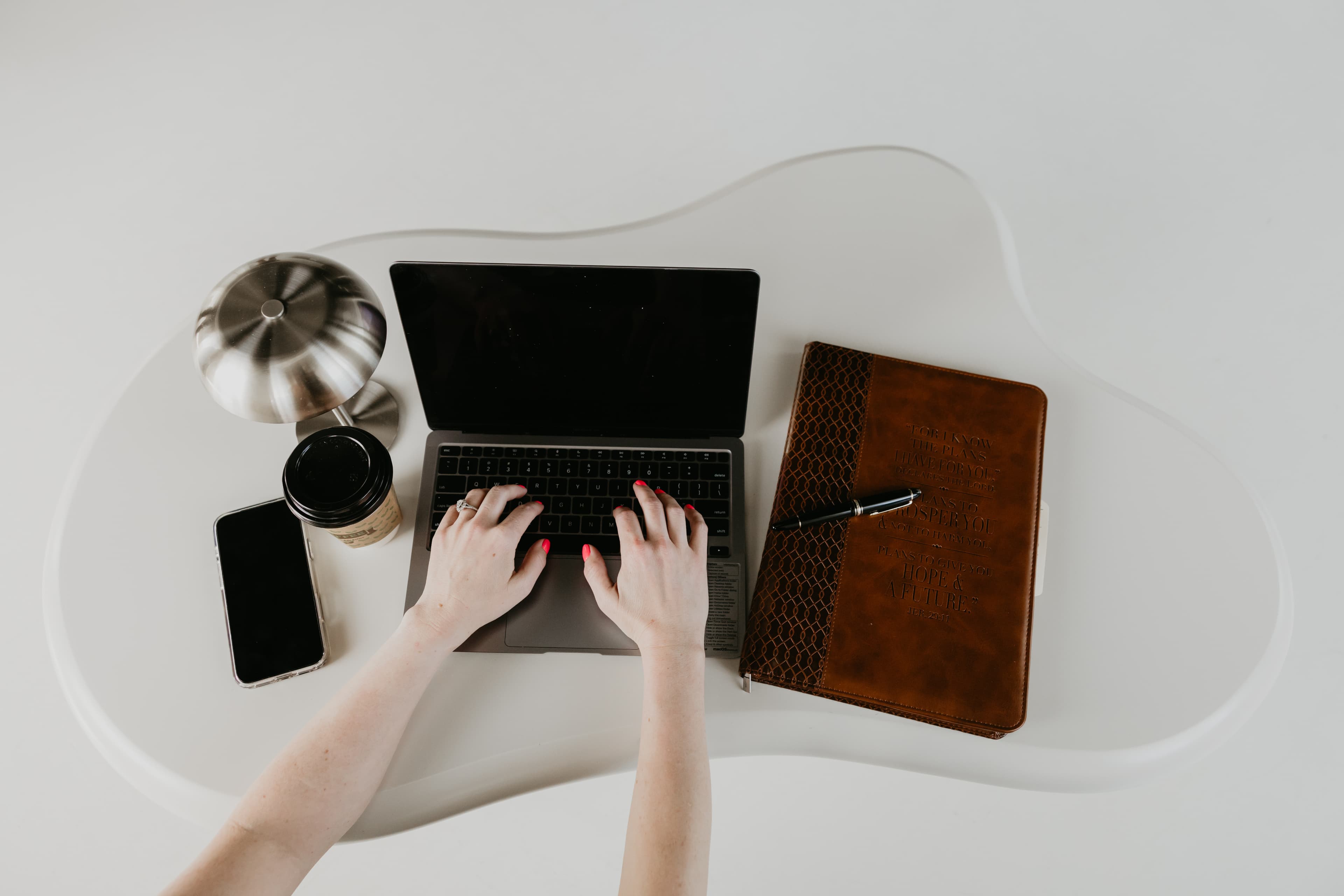 Hands at a laptop with a notebook and coffee — a quiet workspace